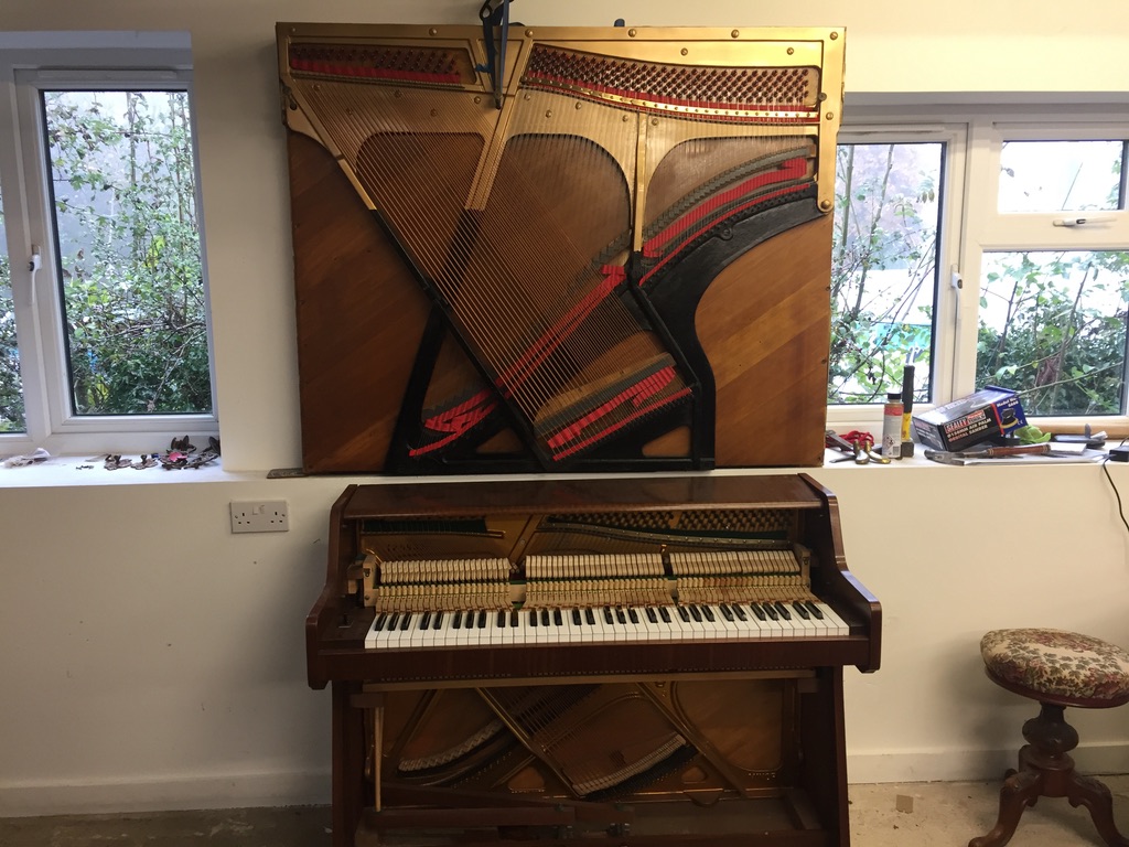 Hanging piano artwork with upright piano underneath